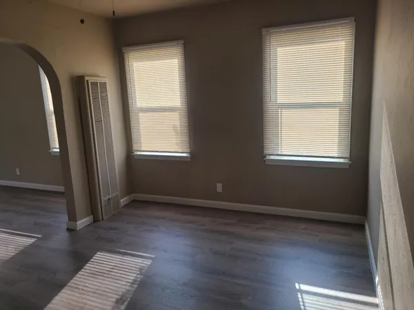 an empty room with wooden floor and windows