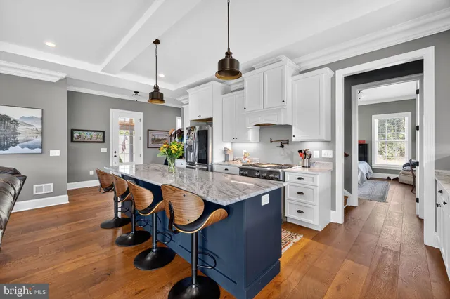 a kitchen with stainless steel appliances granite countertop dining table chairs sink and wooden floor