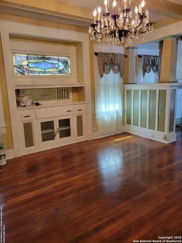 a view of a livingroom with wooden floor a fireplace and chandelier