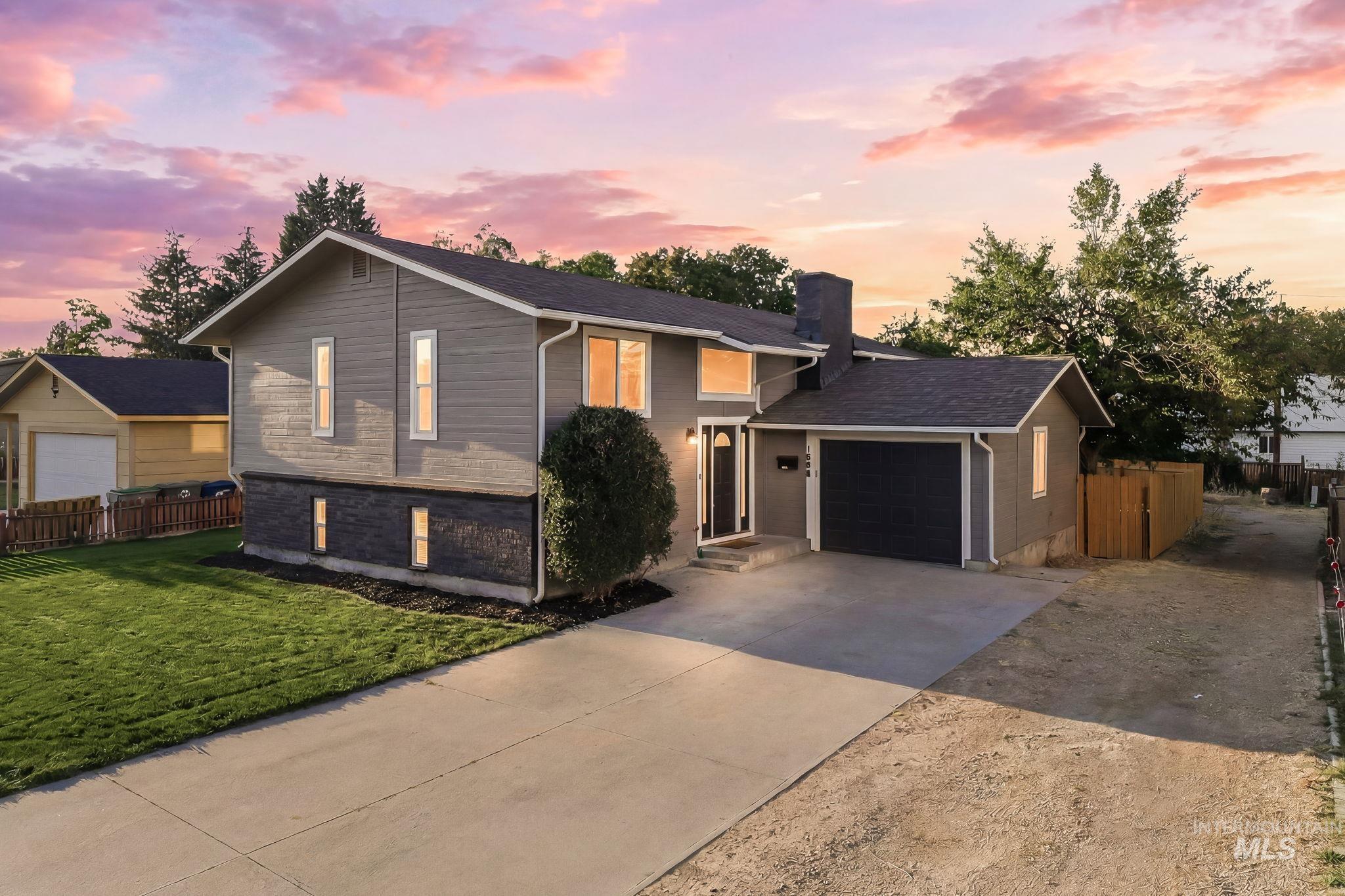 Split-level residence featuring a gray exterior with dark stone accents