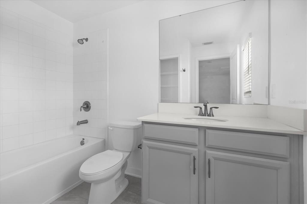 2959 Addison Boulevard St. Cloud, FL 34771 - Photo 19 of 30 a bathroom with a toilet a sink a mirror a bathtub and vanity