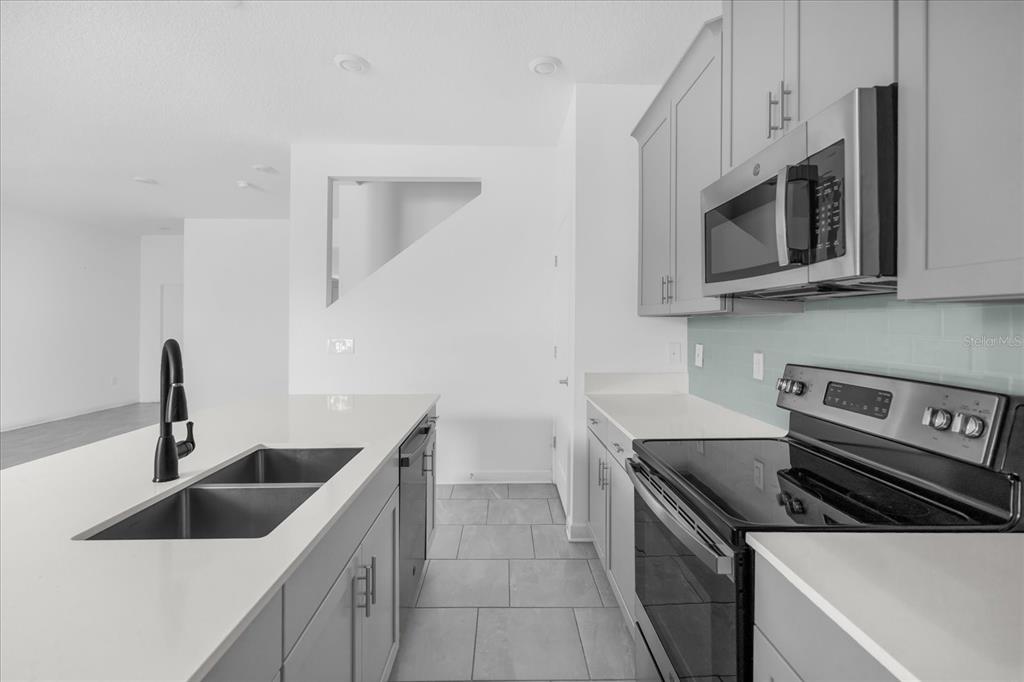 2959 Addison Boulevard St. Cloud, FL 34771 - Photo 5 of 30 a kitchen with white cabinets a sink and stainless steel appliances