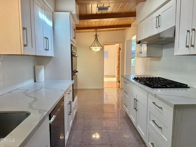 a kitchen with granite countertop a sink stove and cabinets