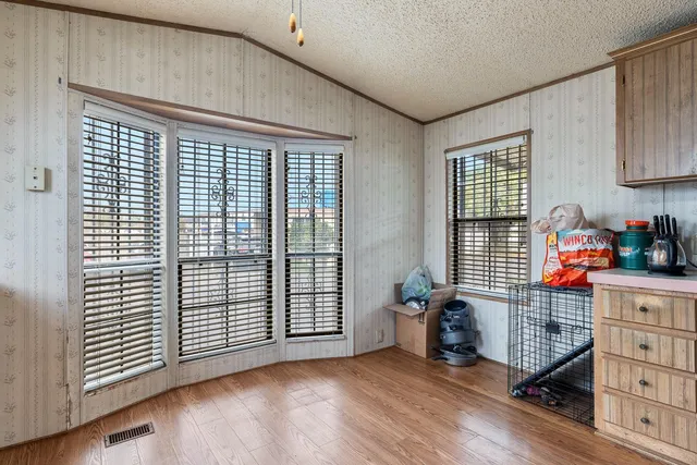 an empty room with wooden floor and windows