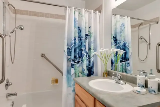 a bathroom with a granite countertop shower sink and mirror