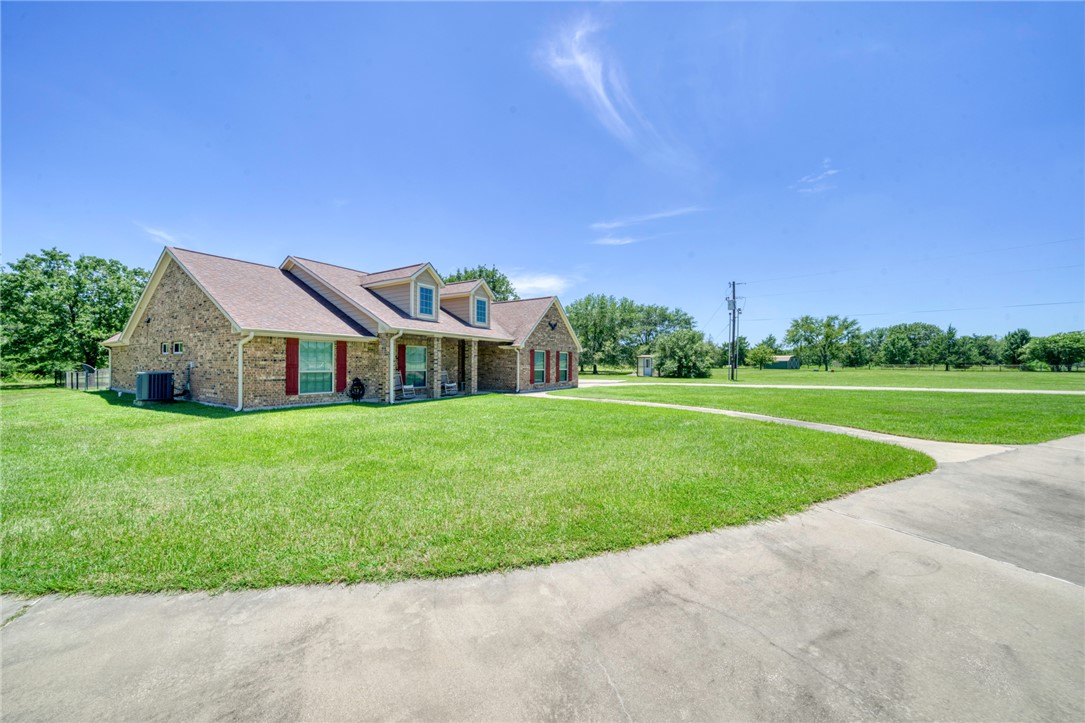 9945 Oxford Cemetery Road Madisonville, TX 77864 - Photo 4 of 42 Cape cod house featuring a front yard, covered porch, brick siding, and a shingled roof