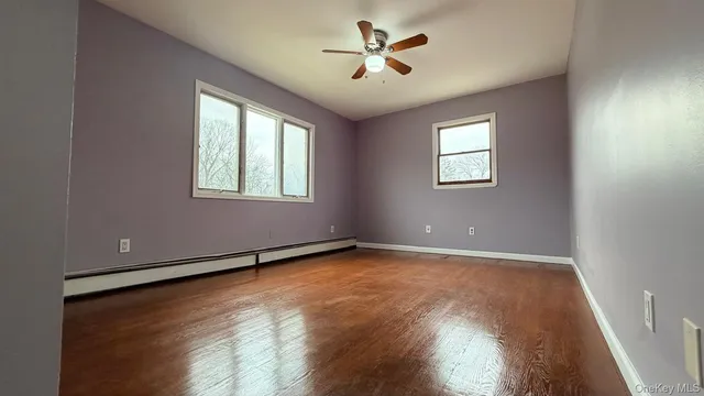 an empty room with windows and ceiling fan