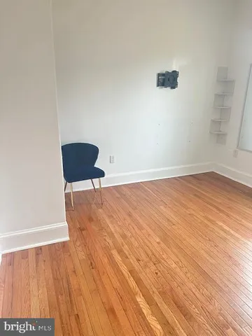 a view of an empty room with wooden floor and a chair