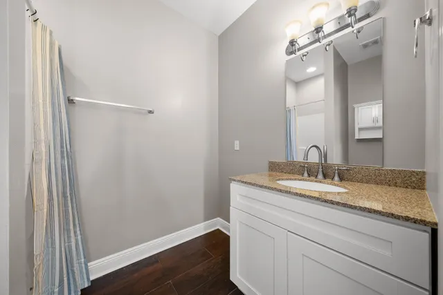 a bathroom with a granite countertop toilet a sink and shower