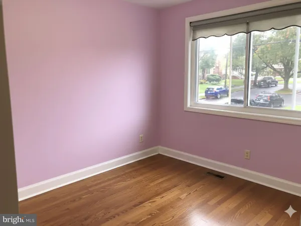 a view of a room that has wooden floor and a window