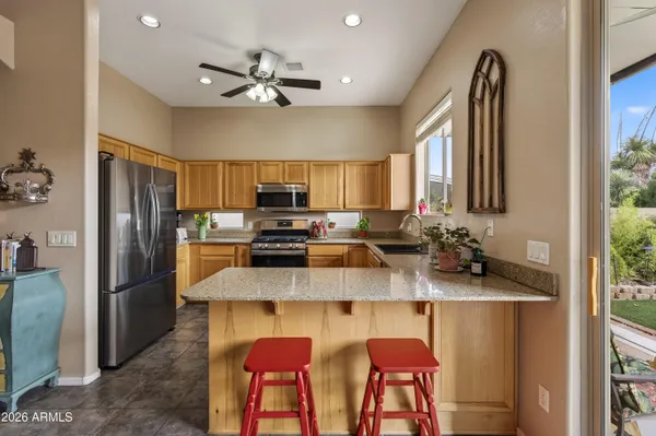 a kitchen with stainless steel appliances granite countertop a sink a stove a refrigerator cabinets and chairs