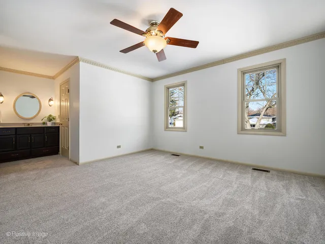an empty room with windows and a ceiling fan