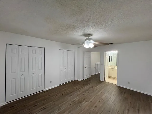 an empty room with wooden floor chandelier fan and windows