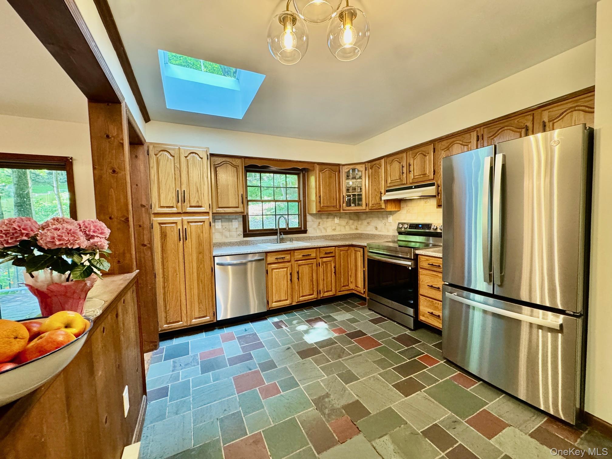 687 Sprout Brook Road Putnam Valley, NY 10579 - Photo 13 of 45 a kitchen with stainless steel appliances granite countertop a refrigerator a sink dishwasher a stove with white cabinets and wooden floor