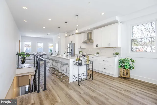 a kitchen with stainless steel appliances kitchen island granite countertop a stove a refrigerator a sink a dining table and chairs with wooden floor
