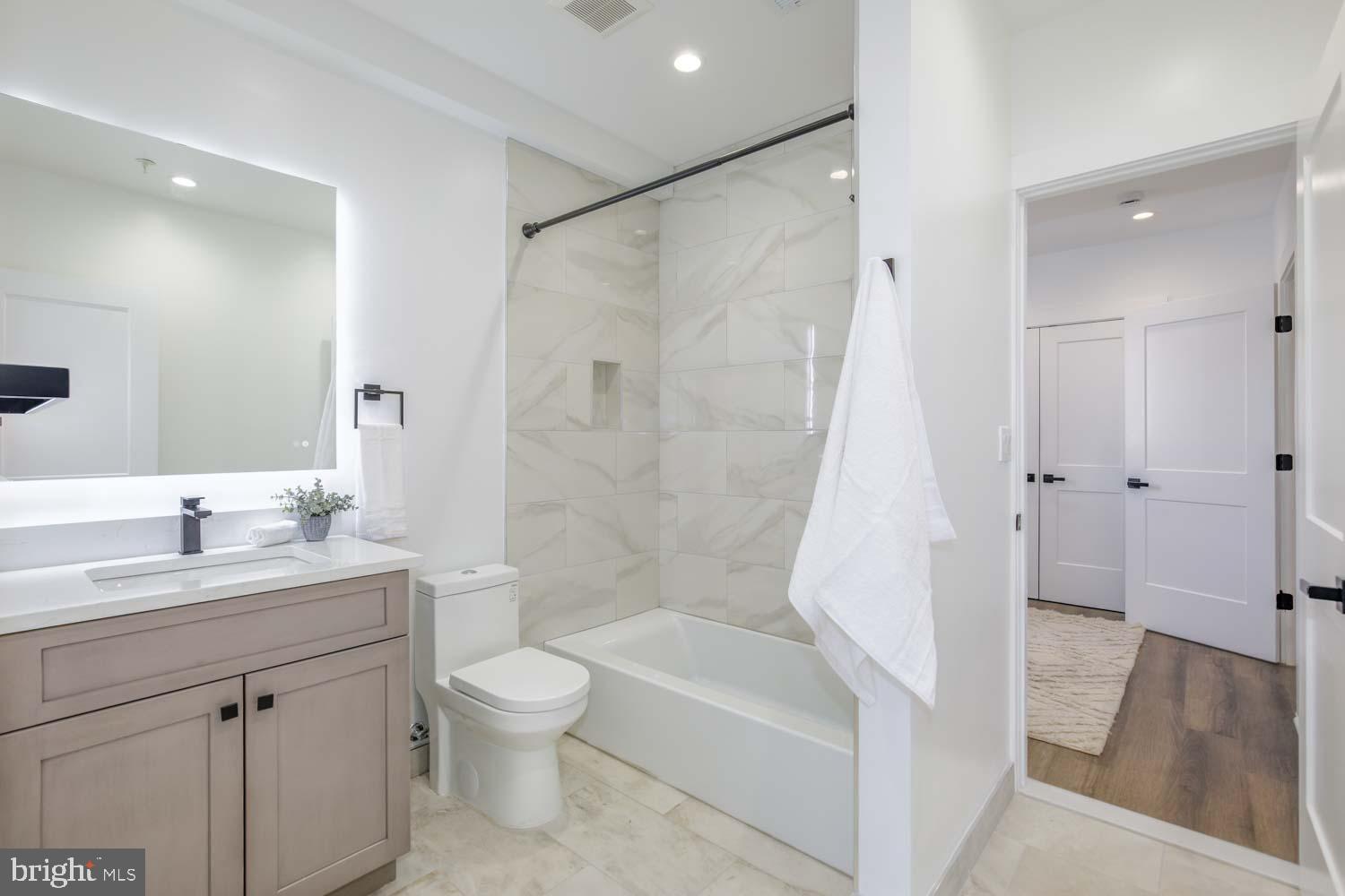 424 Taylor Street Northwest, Unit B Washington, DC 20011 - Photo 37 of 51 a bathroom with a granite countertop sink toilet a large mirror a bathtub and shower