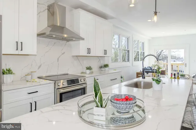 a kitchen with granite countertop stainless steel appliances a sink a stove and a wooden floors