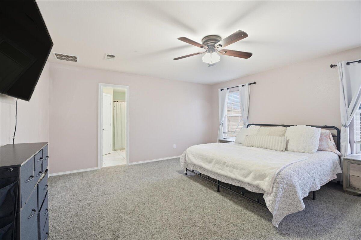 6538 93rd Street Lubbock, TX 79424 - Photo 14 of 27 a bedroom with a large bed and a chandelier