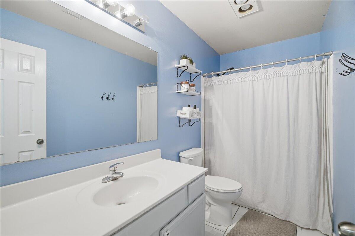 6538 93rd Street Lubbock, TX 79424 - Photo 21 of 27 a bathroom with a sink a toilet and shower curtain