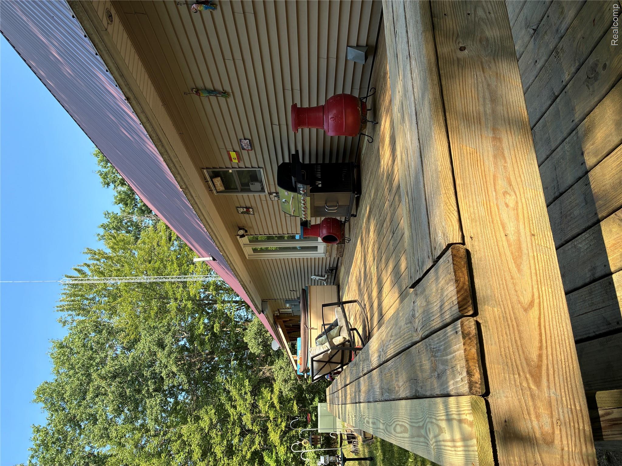 10995 East Isabella County Line Road Coleman, MI 48618 - Photo 67 of 76 Expansive wood deck with an attached hot tub, double glass exterior doors, and a metal roof
