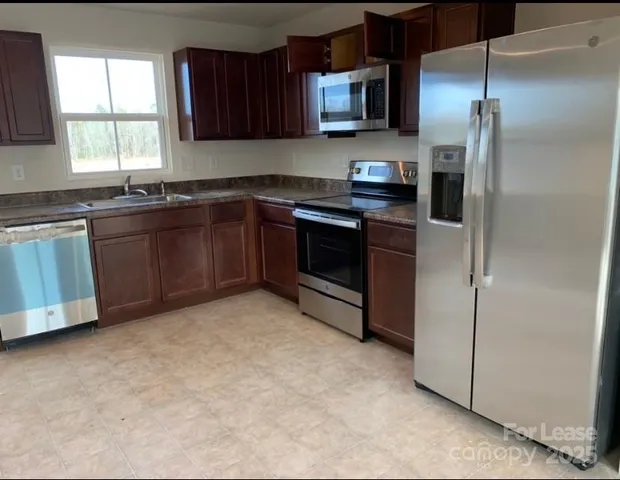 a kitchen with stainless steel appliances granite countertop a stove a sink and a refrigerator