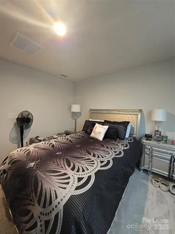 a bedroom with a bed and a lamp on dresser