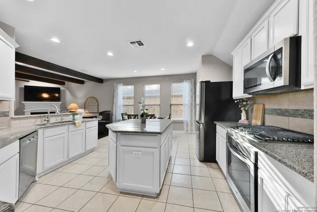 a kitchen with stainless steel appliances granite countertop a stove top oven a sink dishwasher a refrigerator and a microwave