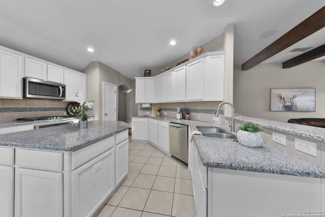 a kitchen with granite countertop a sink stainless steel appliances and white cabinets