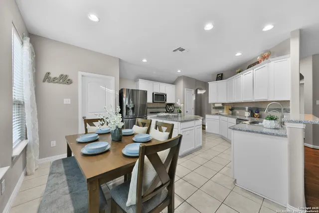 a kitchen with a dining table chairs and refrigerator