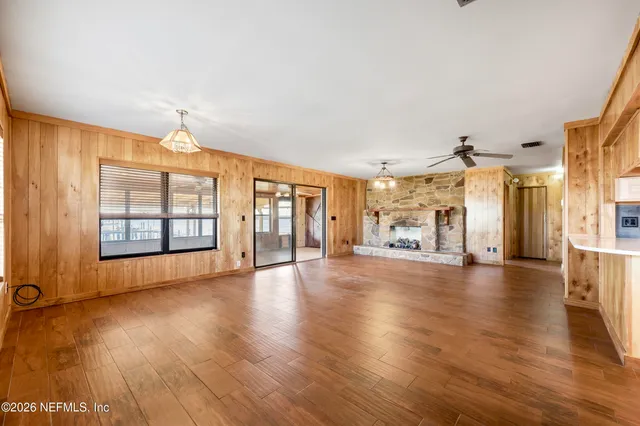 a view of an empty room with window and wooden floor