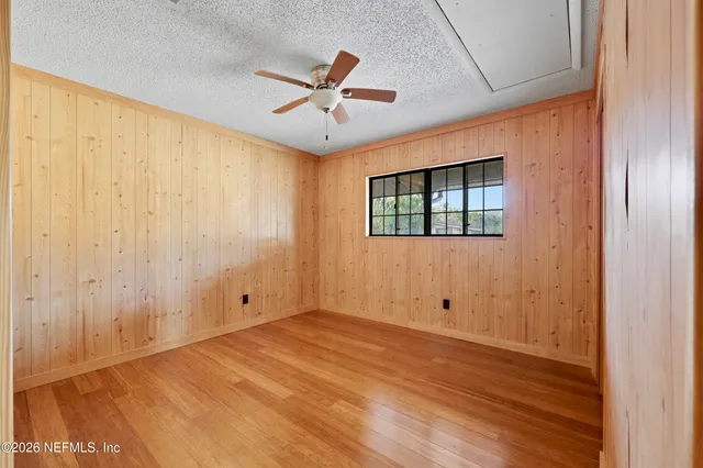 a view of empty room with wooden floor and fan