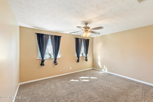 an empty room with windows and fan