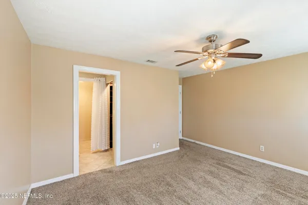 an empty room with a chandelier fan and a window