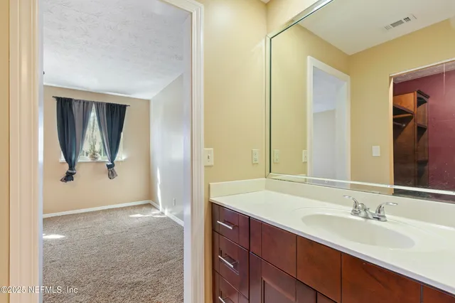 a en suite bathroom with a granite countertop sink and a mirror