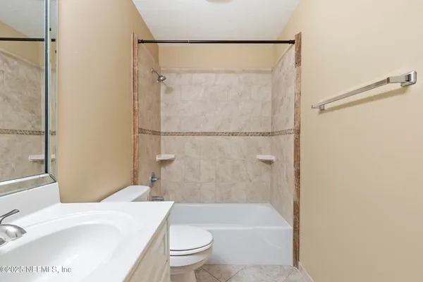 a bathroom with a granite countertop bathtub shower sink vanity and toilet