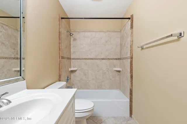 a bathroom with a granite countertop bathtub shower sink vanity and toilet