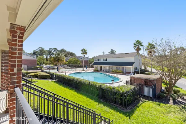 a view of a swimming pool with lawn chairs and potted plants