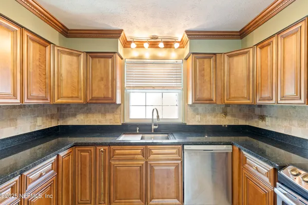 a kitchen with granite countertop white cabinets sink and window