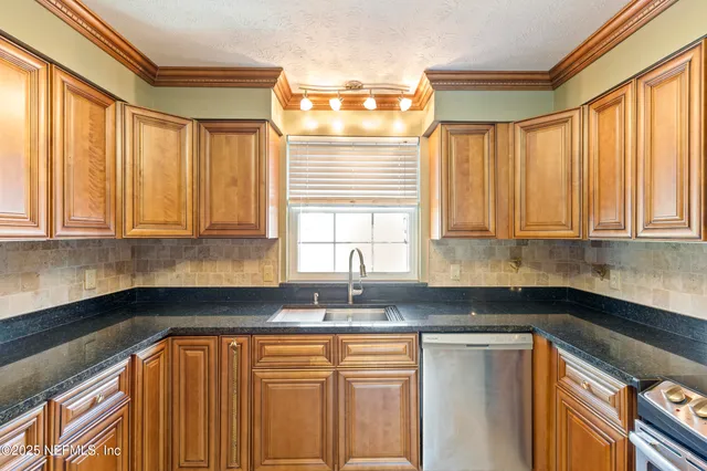 a kitchen with granite countertop white cabinets sink and window