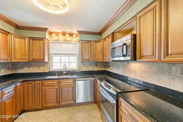 a kitchen with a sink a stove cabinets and a window