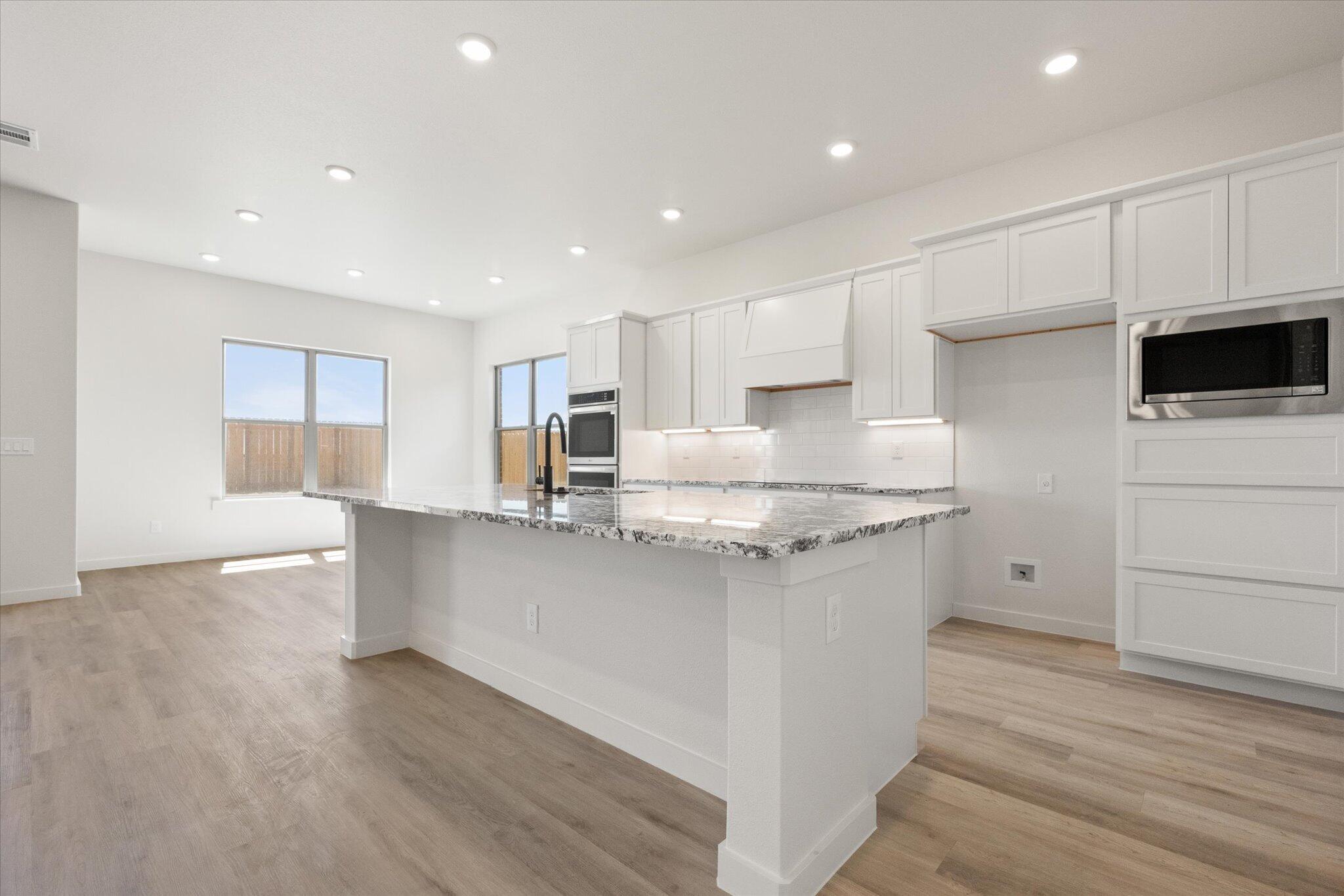 6103 121st Street Lubbock, TX 79424 - Photo 13 of 30 a kitchen with stainless steel appliances granite countertop a sink a stove a refrigerator and white cabinets with wooden floor