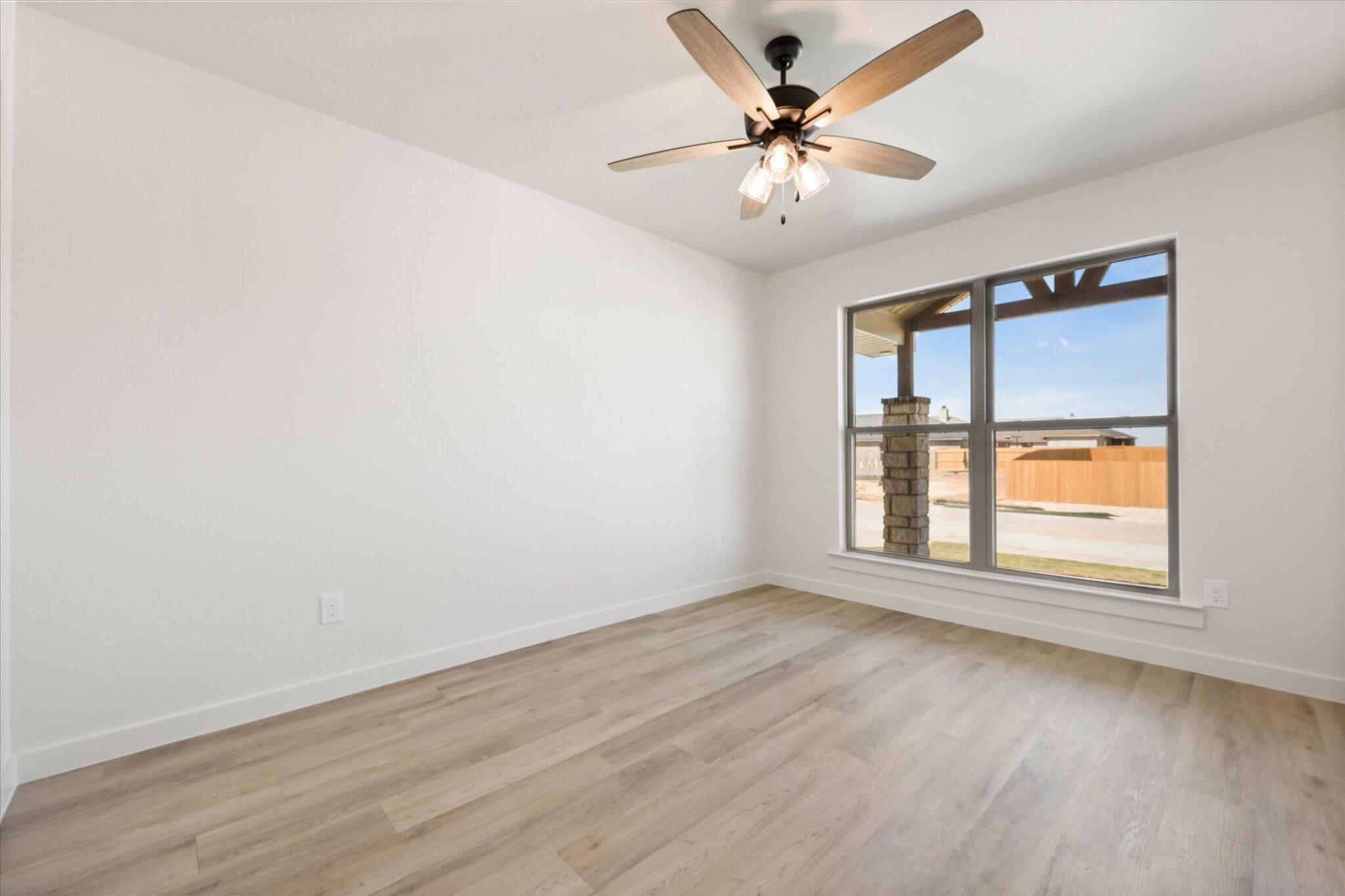 6103 121st Street Lubbock, TX 79424 - Photo 25 of 30 an empty room with wooden floor chandelier fan and windows