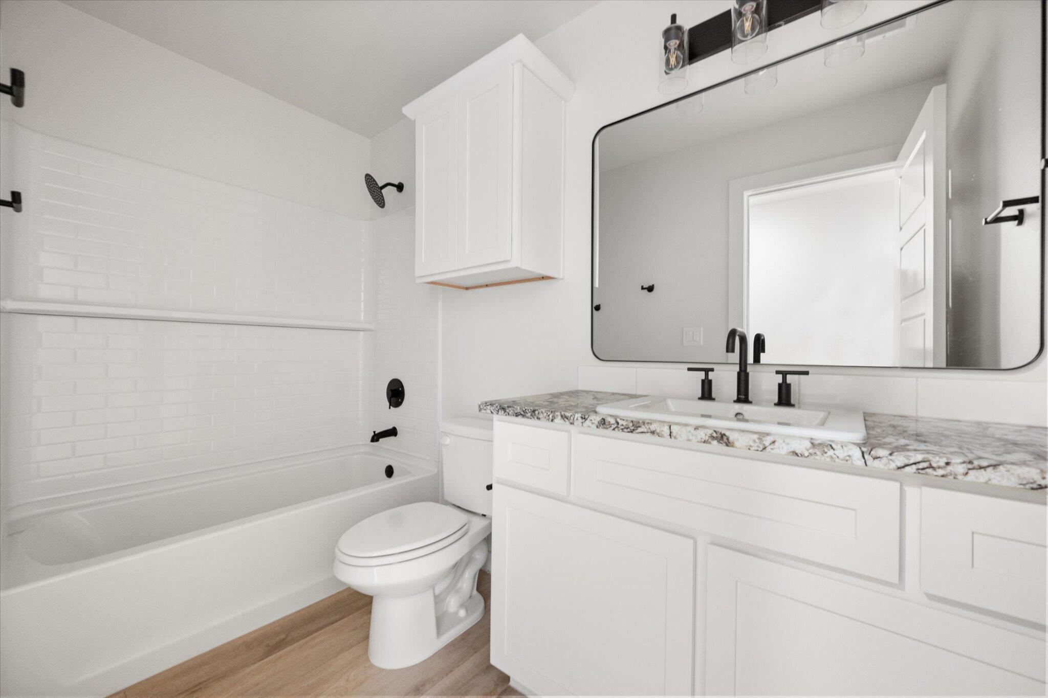 6103 121st Street Lubbock, TX 79424 - Photo 27 of 30 a bathroom with a granite countertop sink toilet a large mirror a bathtub and shower