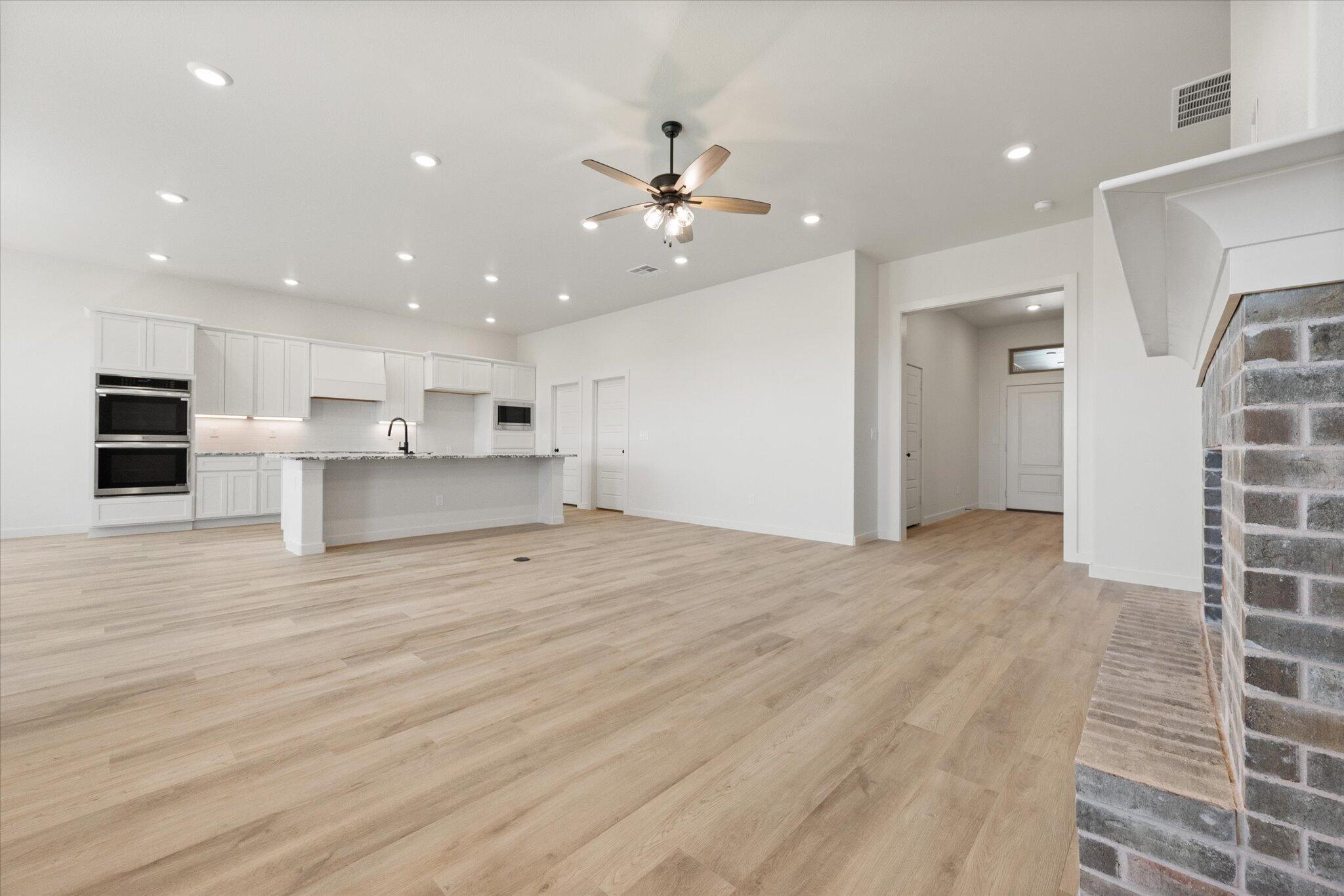 6103 121st Street Lubbock, TX 79424 - Photo 9 of 30 a view of a kitchen with kitchen island a sink wooden floor and a refrigerator