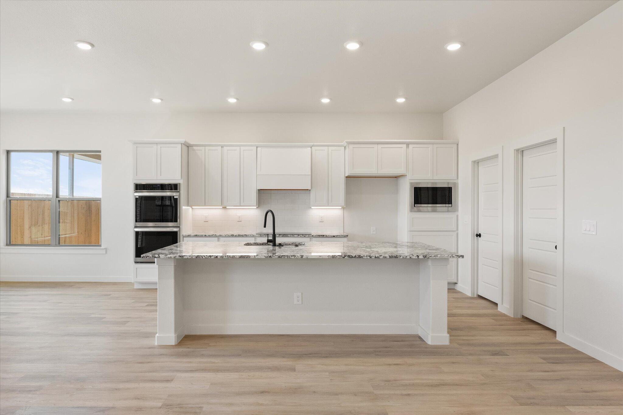 6103 121st Street Lubbock, TX 79424 - Photo 10 of 30 a large kitchen with stainless steel appliances granite countertop a stove a sink and a refrigerator
