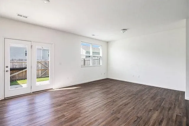 an empty room with wooden floor and windows