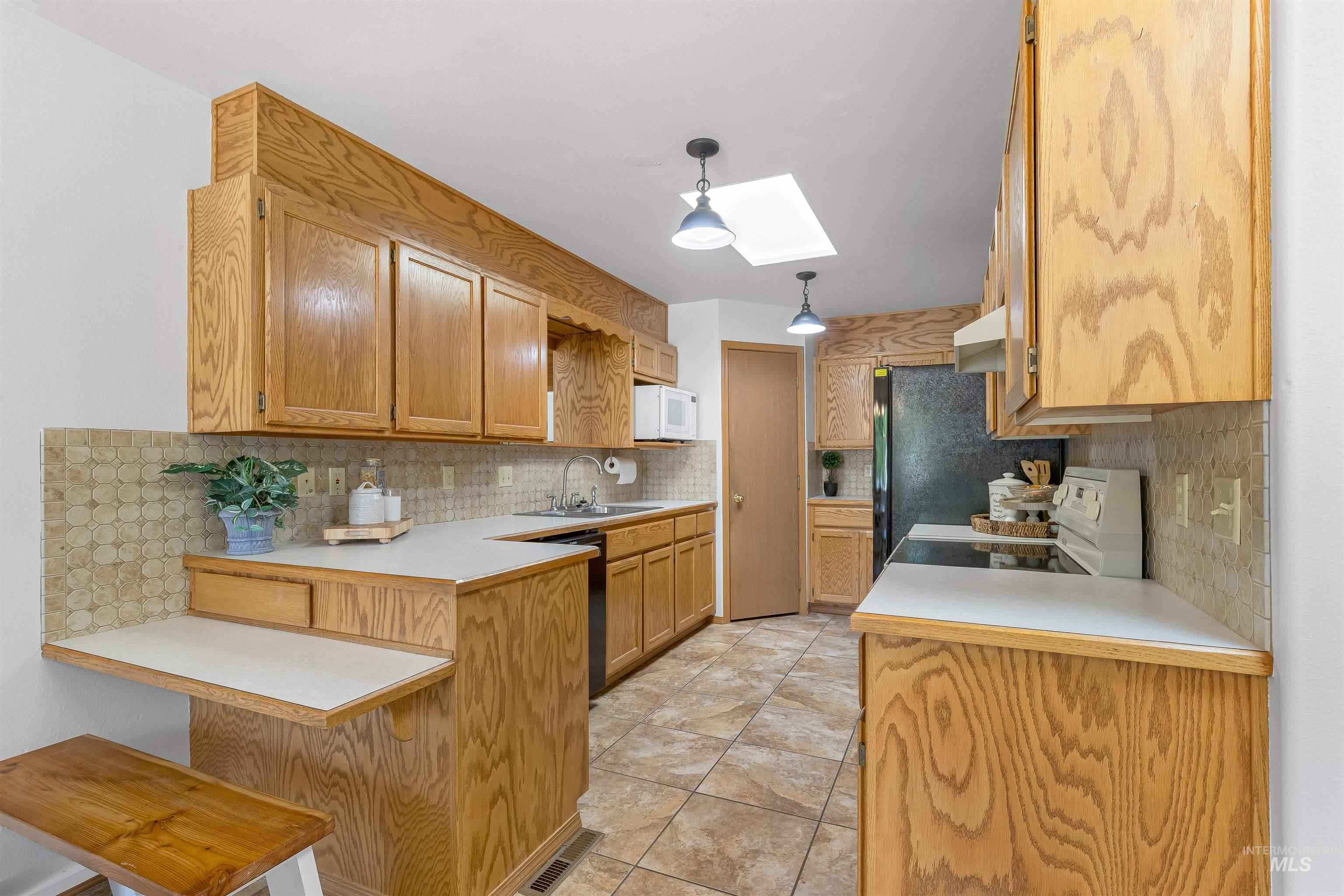 1409 29th Street Lewiston, ID 83501 - Photo 7 of 22 Kitchen featuring white microwave, range, a peninsula, and tasteful backsplash