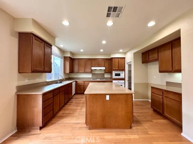 a large kitchen with stainless steel appliances granite countertop a large counter top a stove and a sink