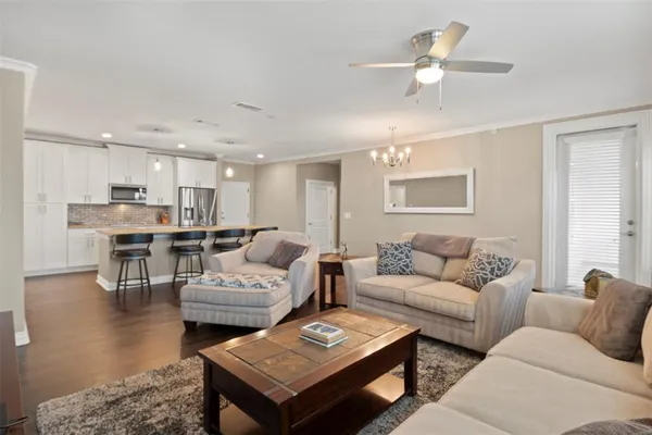 a living room with furniture kitchen view and a chandelier