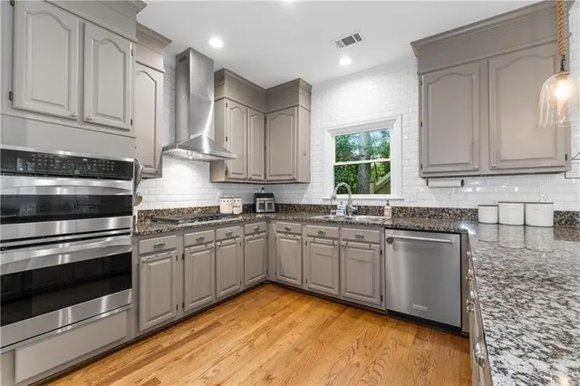 a kitchen with stainless steel appliances granite countertop a stove a sink and a microwave